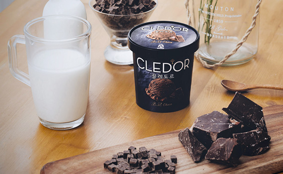 탁자 위에 끌레도르 제품이 우유컵, 초콜릿 조각들과 함께 놓여있는 사진